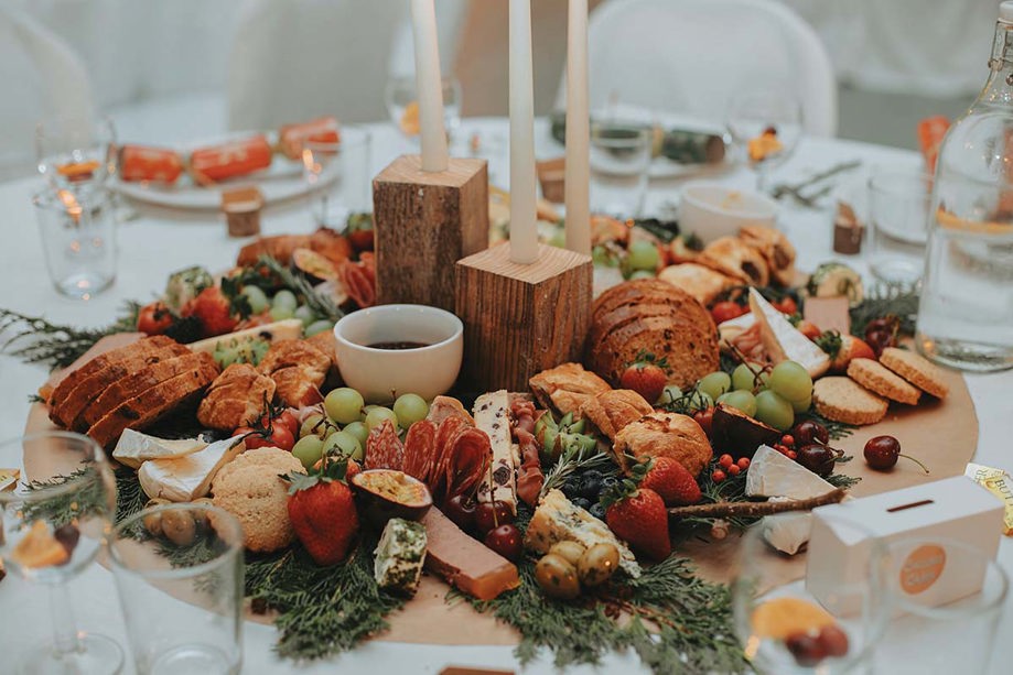 display of meats, cheeses, bread and fruit in the middle of a round table for guests to share 